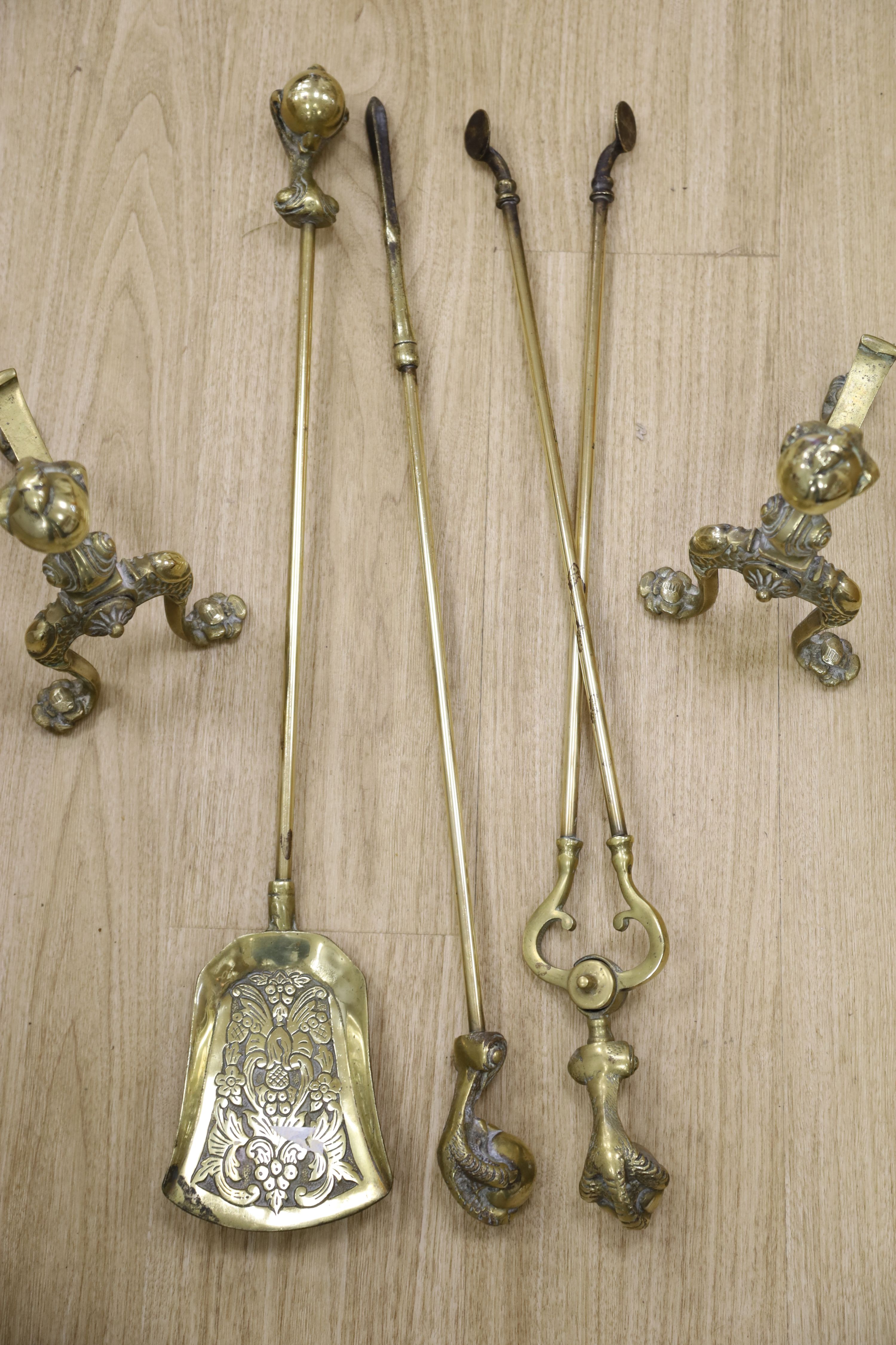 A set of three brass claw and ball fire implements and dogs